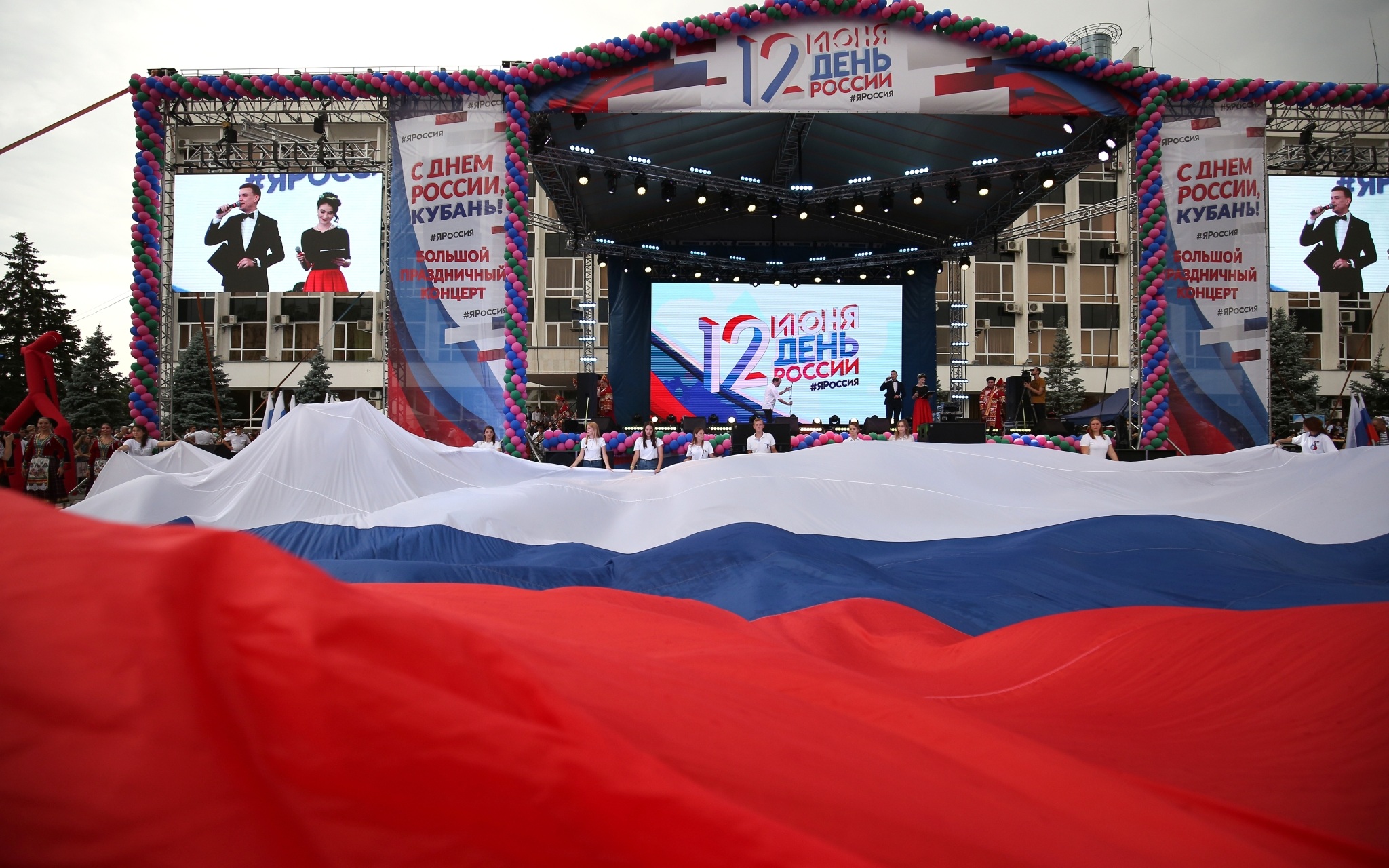 Жители города разворачивают полотнище российского флага на праздновании Дня России в Краснодаре.